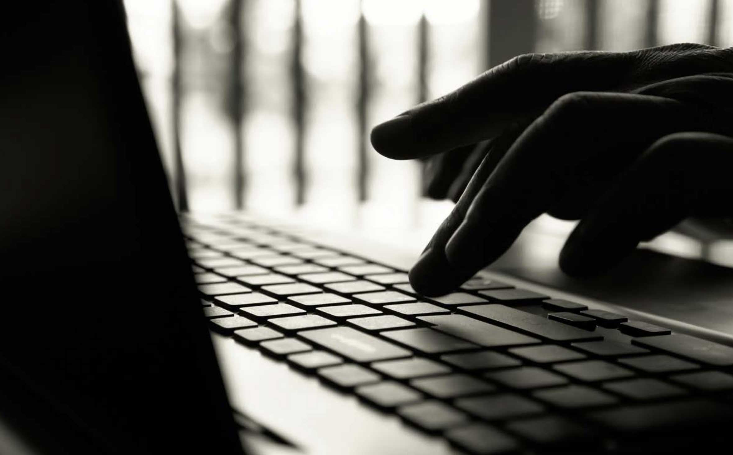 black and white picture - hand typing on a laptop keyboard